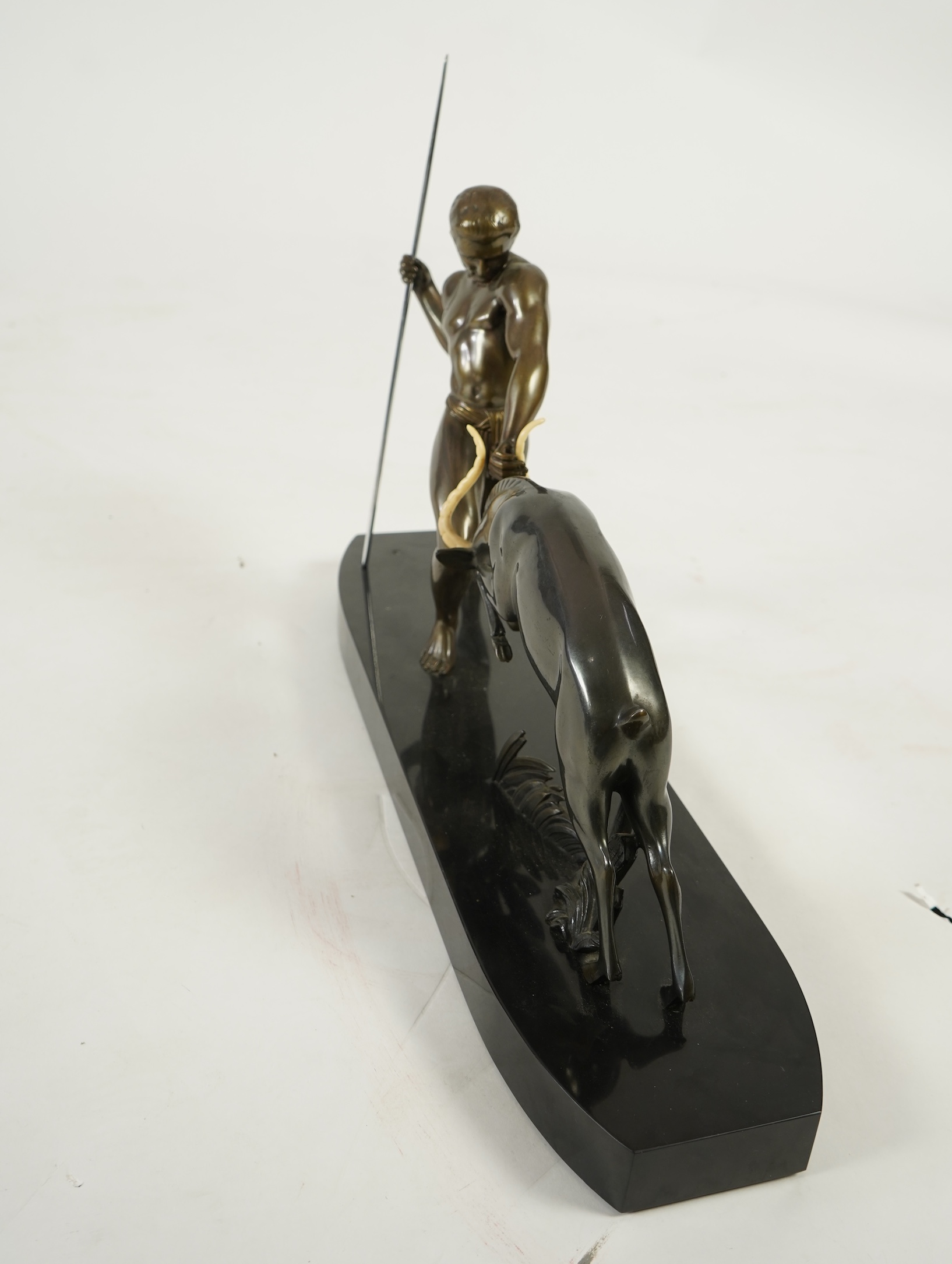 Attributed to Zoltan Kovasz (Romanian, 1883-1952), a bronzed spelter male hunter holding a chromed spear, with springbok, on a polished slate base